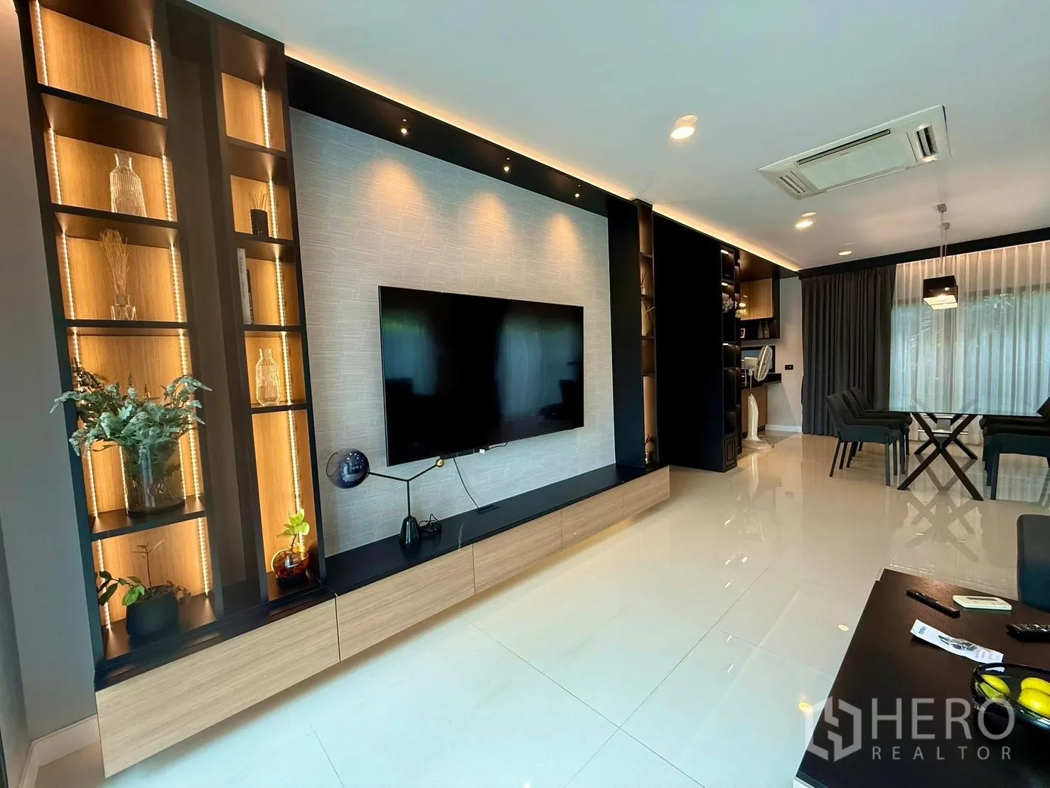 Detached House for rent in Bang Kapi, Bangkok - Contemporary living room with feature TV wall, illuminated shelves and glossy floors.
