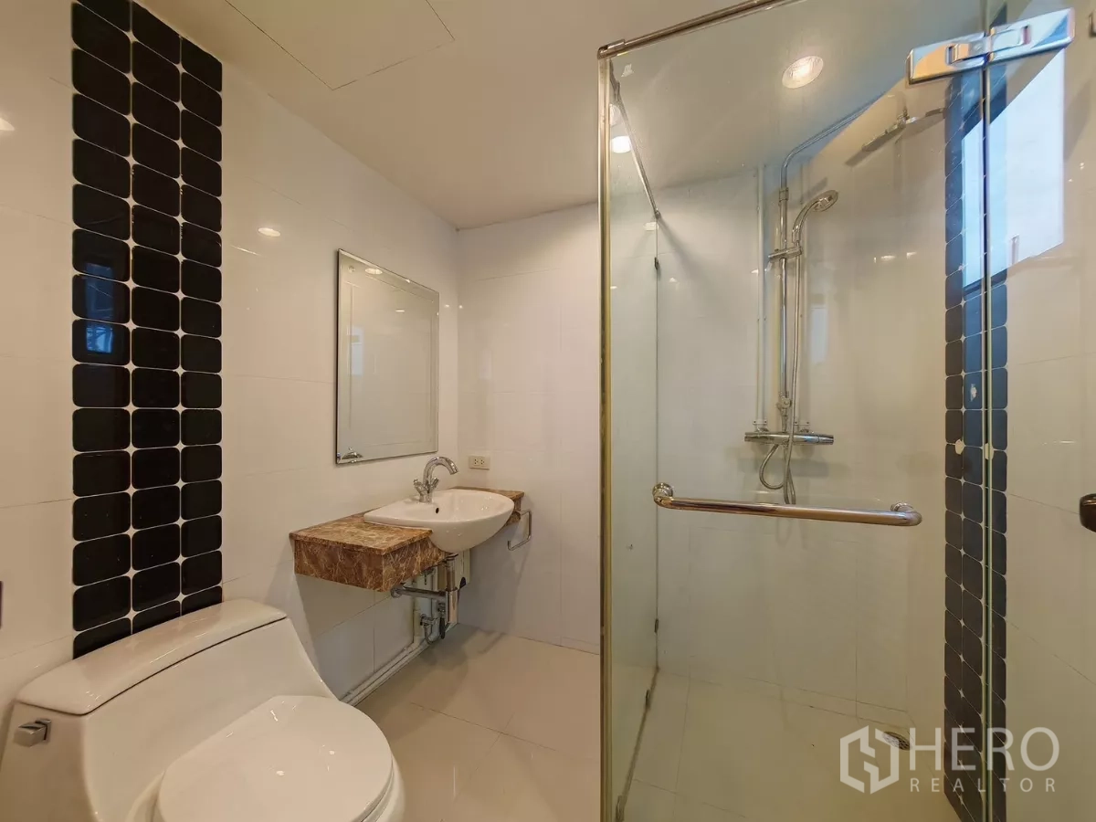 คอนโด ให้เช่าในPathum Wan, Bangkok - ห้องน้ำพร้อมห้องอาบน้ำกระจก โถสุขภัณฑ์ และแถบกระเบื้องสีดำแนวตั้ง