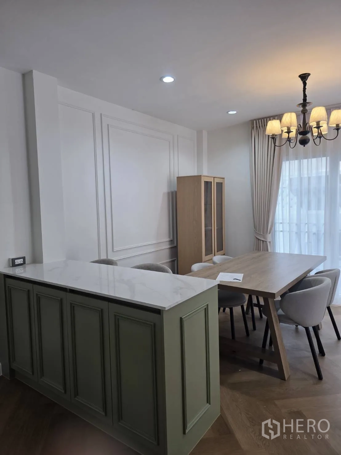 Detached House for sale in Lam Luk Ka, Pathum Thani - Open dining space with green paneled island topped in marble and classic chandelier.