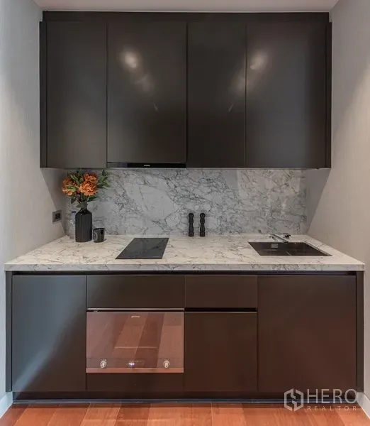 คอนโด ขายในWatthana, Bangkok - ครัวบิลต์อินสมัยใหม่ เคาน์เตอร์หินอ่อน เตาไฟฟ้า และตู้เก็บของสีเข้ม