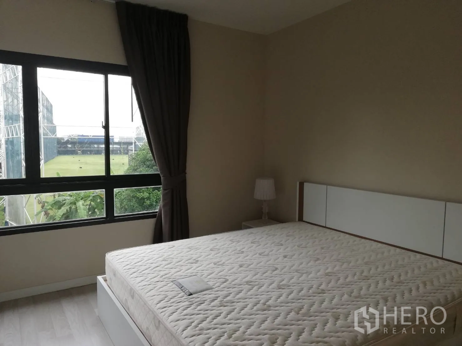 Townhouse for rent in Bang Kapi, Bangkok - Master bedroom with king-size bed and large window overlooking a golf driving range.