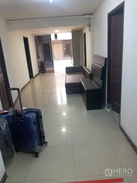 พื้นที่ขายปลีก ให้เช่าในKhlong Toei, Bangkok - โถงทางเดินพื้นกระเบื้องพร้อมโซฟาสีเข้มและประตูหลายบาน