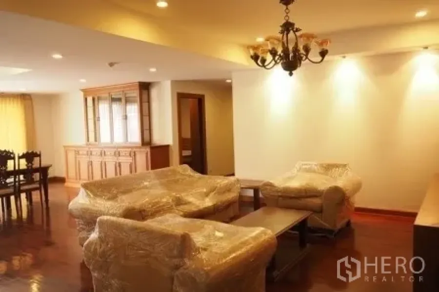 อพาร์ทเมนท์ ให้เช่าในPathum Wan, Bangkok - อีกมุมของห้องนั่งเล่น พร้อมโคมระย้า ชุดโซฟา และตู้โชว์ไม้