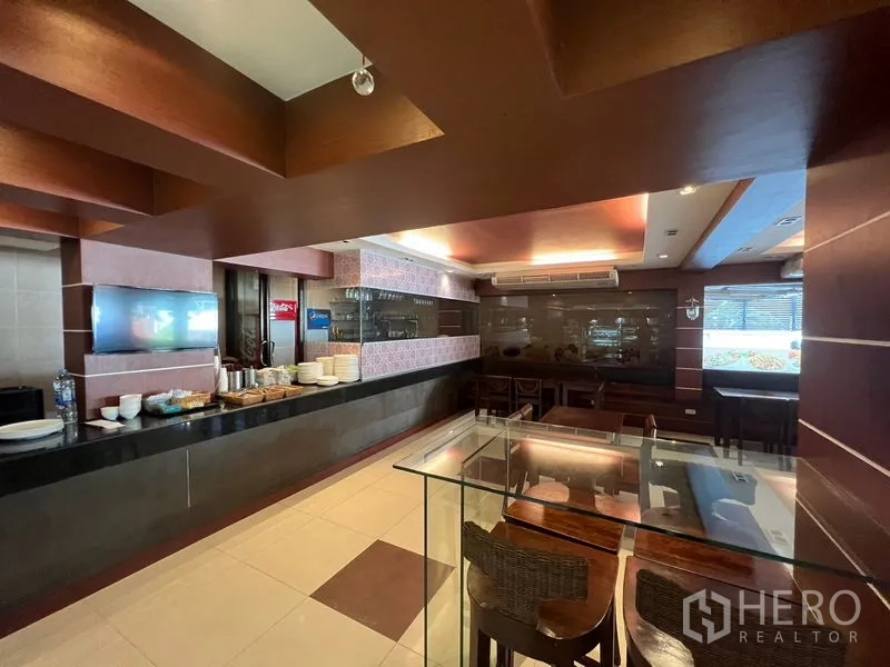 零售空间 出租或出售在Khlong Toei, Bangkok - 餐饮式出餐台与玻璃展示柜，堂食区和吊顶灯光。