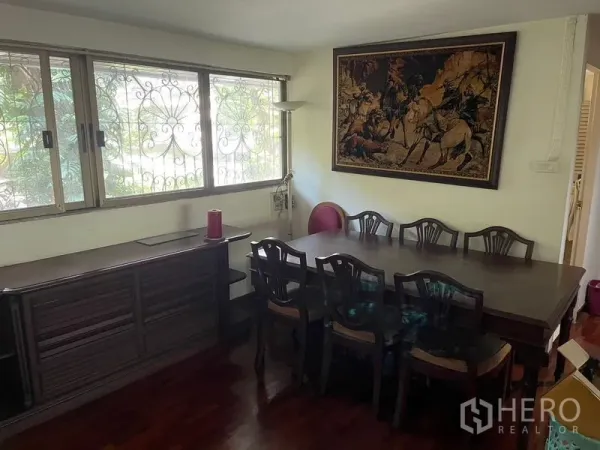 สำนักงานที่บ้าน ให้เช่าในWatthana, Bangkok - มุมรับประทานอาหาร โต๊ะไม้ยาว ตู้ข้างหน้าต่างเหล็กดัด และภาพติดผนัง