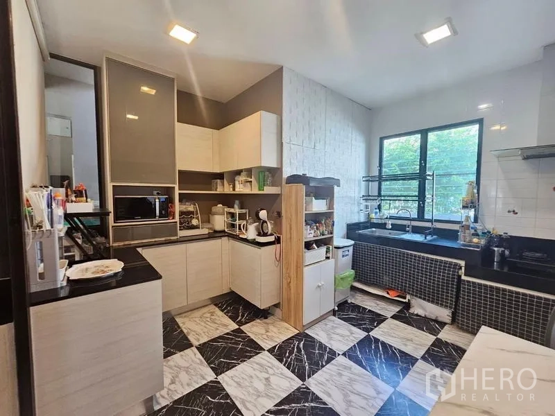 Detached House for sale in Prawet, Bangkok - Full view of modern Thai kitchen with L‑shaped cabinets, black countertops and chequered floor.