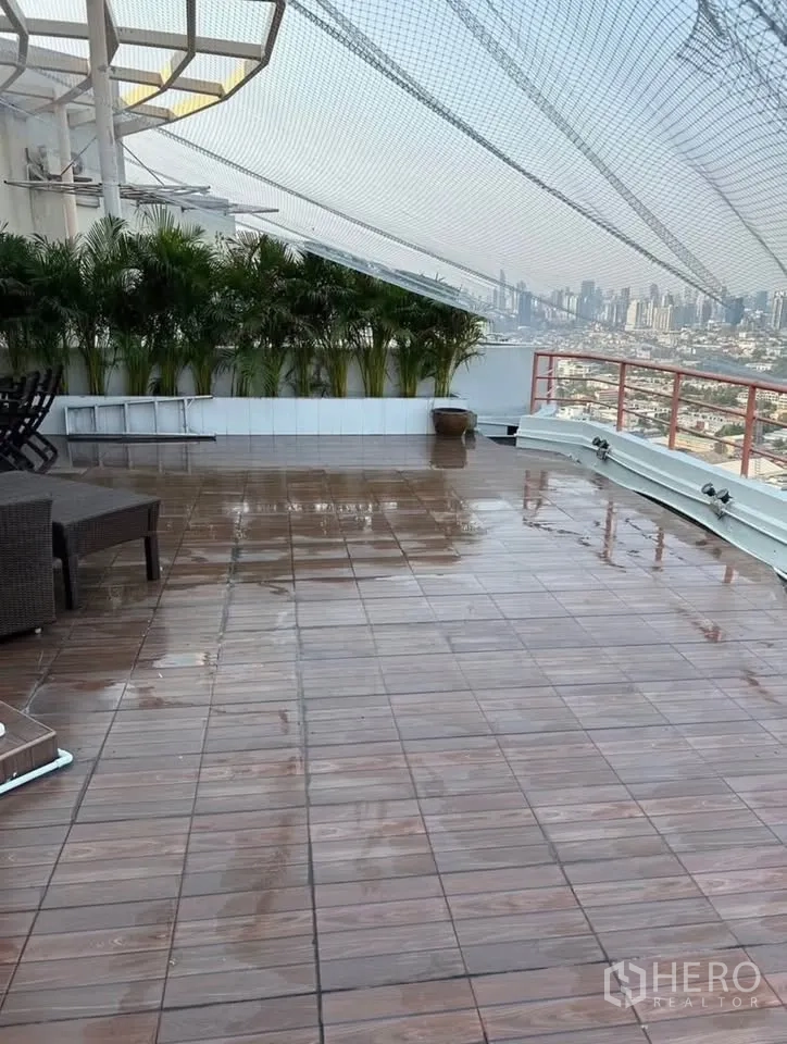 Condominium for rent or sale in Yan Nawa, Bangkok - Expansive private rooftop terrace with wood tiles, potted palms, net canopy and panoramic river and skyline views.