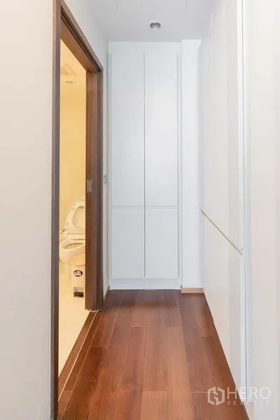 Condominium for rent - Hallway with wooden flooring and tall storage cabinets next to the bathroom.