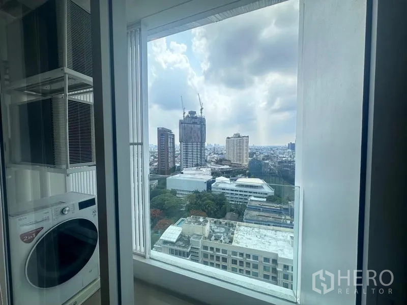 คอนโด ให้เช่า - พื้นที่ซักล้างพร้อมเครื่องซักผ้า–อบผ้า ข้างหน้าต่างบานใหญ่เห็นวิวสกายไลน์กรุงเทพฯ