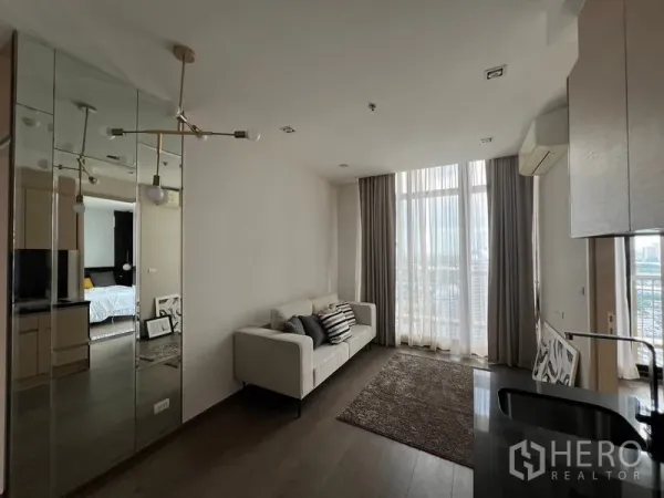 คอนโด ขาย - ห้องนั่งเล่นโปร่งสว่าง โซฟาสีขาวและกระจกสูงจากพื้นจรดเพดาน