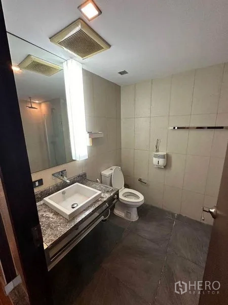 Condominium for sale in Bang Rak, Bangkok - Modern bathroom with granite vanity, square basin and tiled walls.