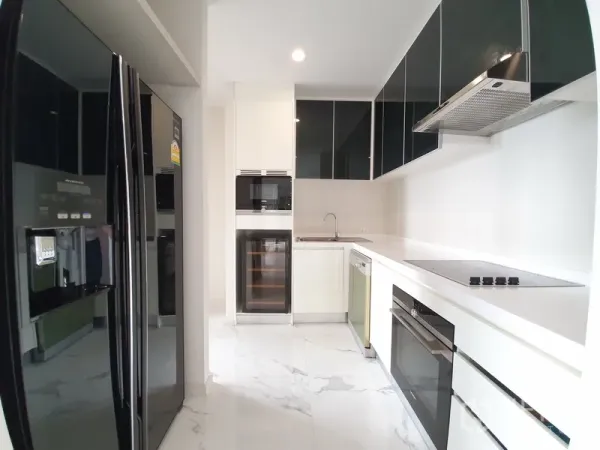 Condominium for rent in Pathum Wan, Bangkok - Modern enclosed kitchen with glossy cabinets, oven, cooktop, wine fridge, dishwasher and a double-door refrigerator.