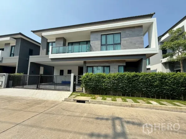 Townhouse for rent - Front view of contemporary townhouse with long balcony, gated driveway and tall privacy hedge.