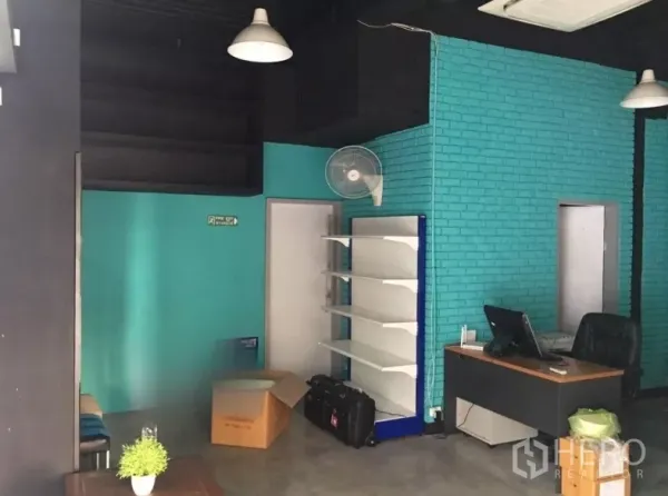 Retail Space for rent in Khlong Toei, Bangkok - Interior corner with teal brick feature wall, display shelving, desk, and pendant lights.