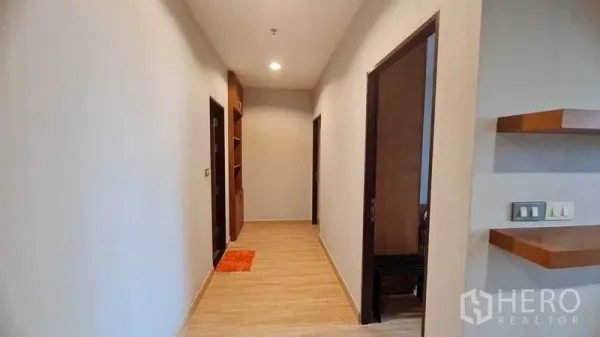 Condominium for rent or sale in Watthana, Bangkok - Bright hallway with wood floors, recessed lighting, and built-in shelving leading to bedrooms and bathroom.