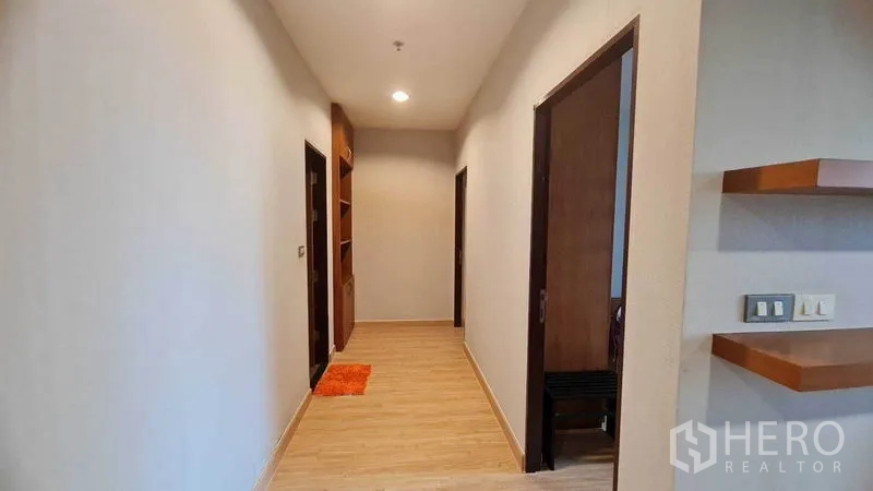 Condominium for rent or sale in Watthana, Bangkok - Bright hallway with wood floors, recessed lighting, and built-in shelving leading to bedrooms and bathroom.