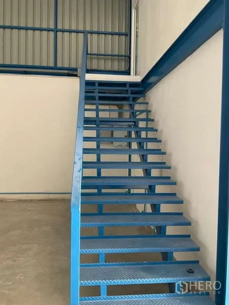 Warehouse for rent in Bang Bua Thong, Nonthaburi - Blue metal staircase leading to a mezzanine or office area inside the warehouse.
