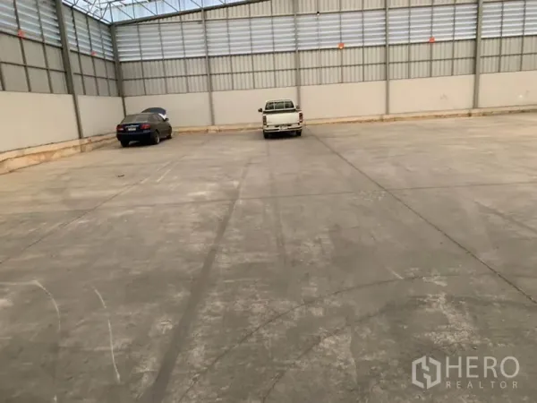 货栈 出租在Khlong Sam Wa, Bangkok - 仓库内的装卸与停车区，混凝土地面，可见两辆停放的车辆。