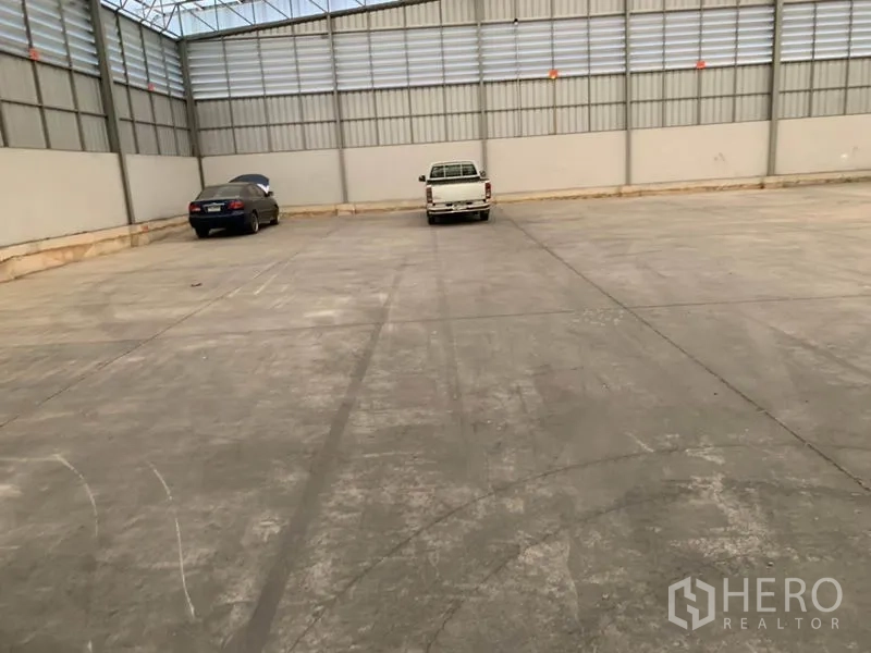 货栈 出租在Khlong Sam Wa, Bangkok - 仓库内的装卸与停车区，混凝土地面，可见两辆停放的车辆。