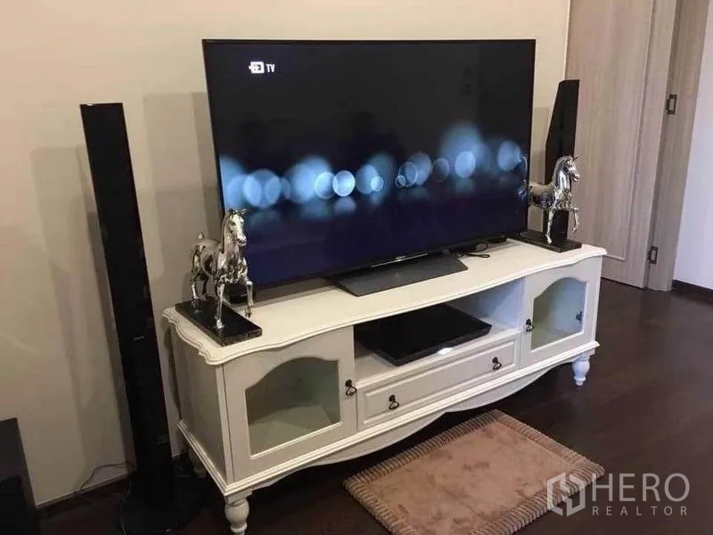 คอนโด ให้เช่าในWatthana, Bangkok - ทีวีจอแบนบนตู้วางทีวีสีขาวพร้อมลำโพงสูงในห้องนั่งเล่น