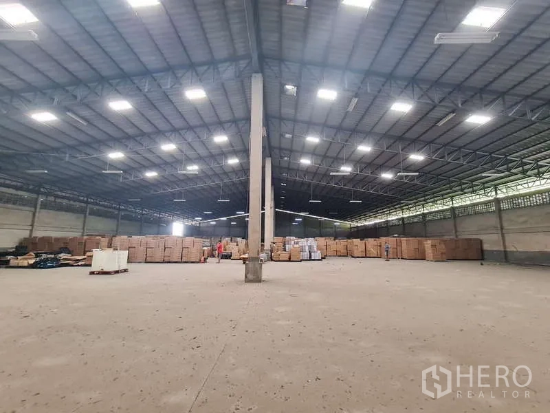 Warehouse for rent - Open storage area with center column and palletized goods at the rear.