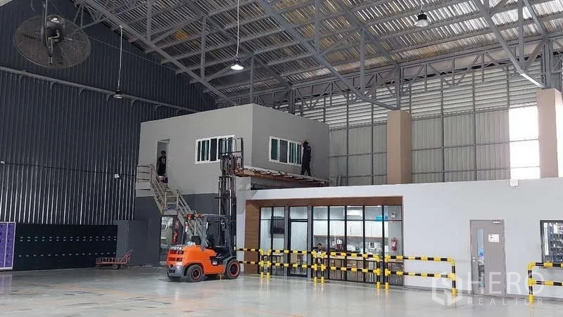 Warehouse for rent in Rat Burana, Bangkok - Large industrial hall featuring a raised office, glass-front meeting room and high roof with industrial fans.