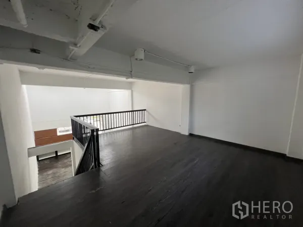 零售空间 出租在Watthana, Bangkok - 夹层配黑色金属栏杆，可俯瞰一层挑高店铺区域。