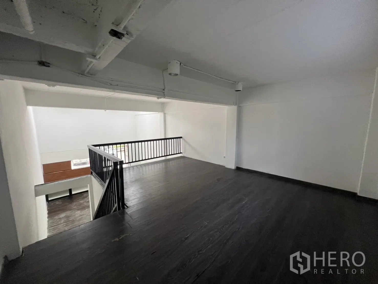 零售空间 出租在Watthana, Bangkok - 夹层配黑色金属栏杆，可俯瞰一层挑高店铺区域。