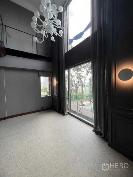 公寓 出售在Khlong Toei, Bangkok - 高挑房间，造型吊灯与长窗帘，俯瞰泳池甲板。