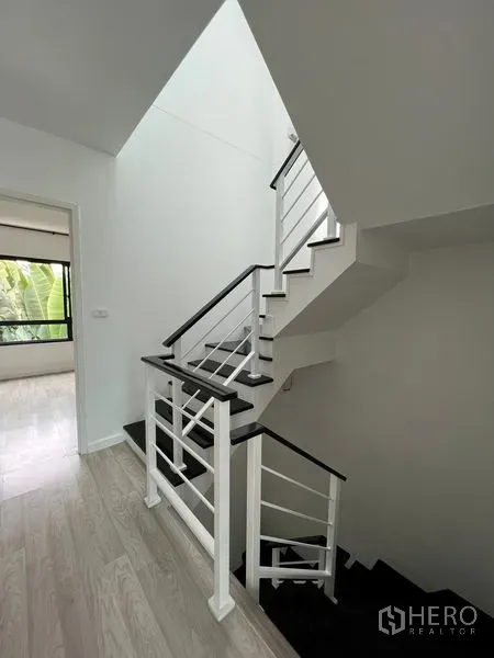ทาวน์เฮาส์ ขายในBang Kapi, Bangkok - บันไดสไตล์โมเดิร์นโทนขาวดำพร้อมราวโลหะในโถงสว่าง