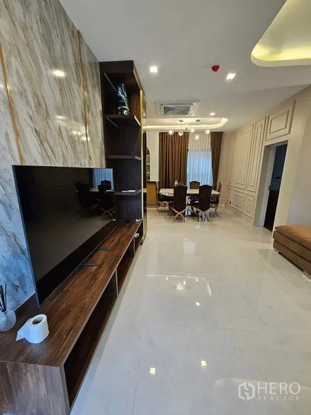 Detached House for sale in Mueang Pathum Thani, Pathum Thani - TV wall with marble feature and wooden console facing the dining space.