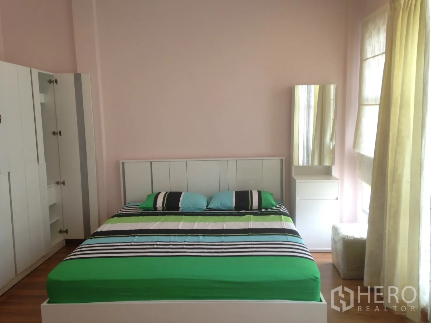 ทาวน์เฮาส์ ให้เช่าในWang Thonglang, Bangkok - ห้องนอนใหญ่ เตียงคู่ ตู้เสื้อผ้าสีขาว โต๊ะเครื่องแป้ง และผนังสีชมพูอ่อน