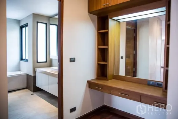 บ้าน ให้เช่าในKhlong Toei, Bangkok - มุมโต๊ะเครื่องแป้งบิวท์อินไม้พร้อมชั้นวาง ใกล้ห้องน้ำสไตล์โมเดิร์นที่มีหน้าต่าง