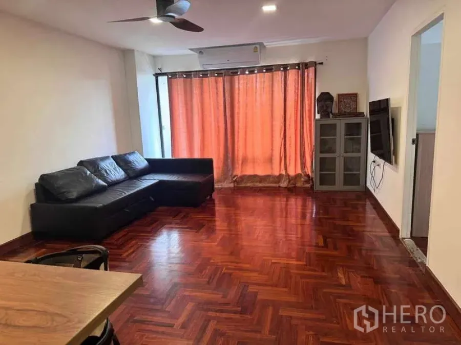 公寓 出租在Sathon, Bangkok - 客厅另一角度，转角沙发、吊扇与大幅窗帘。