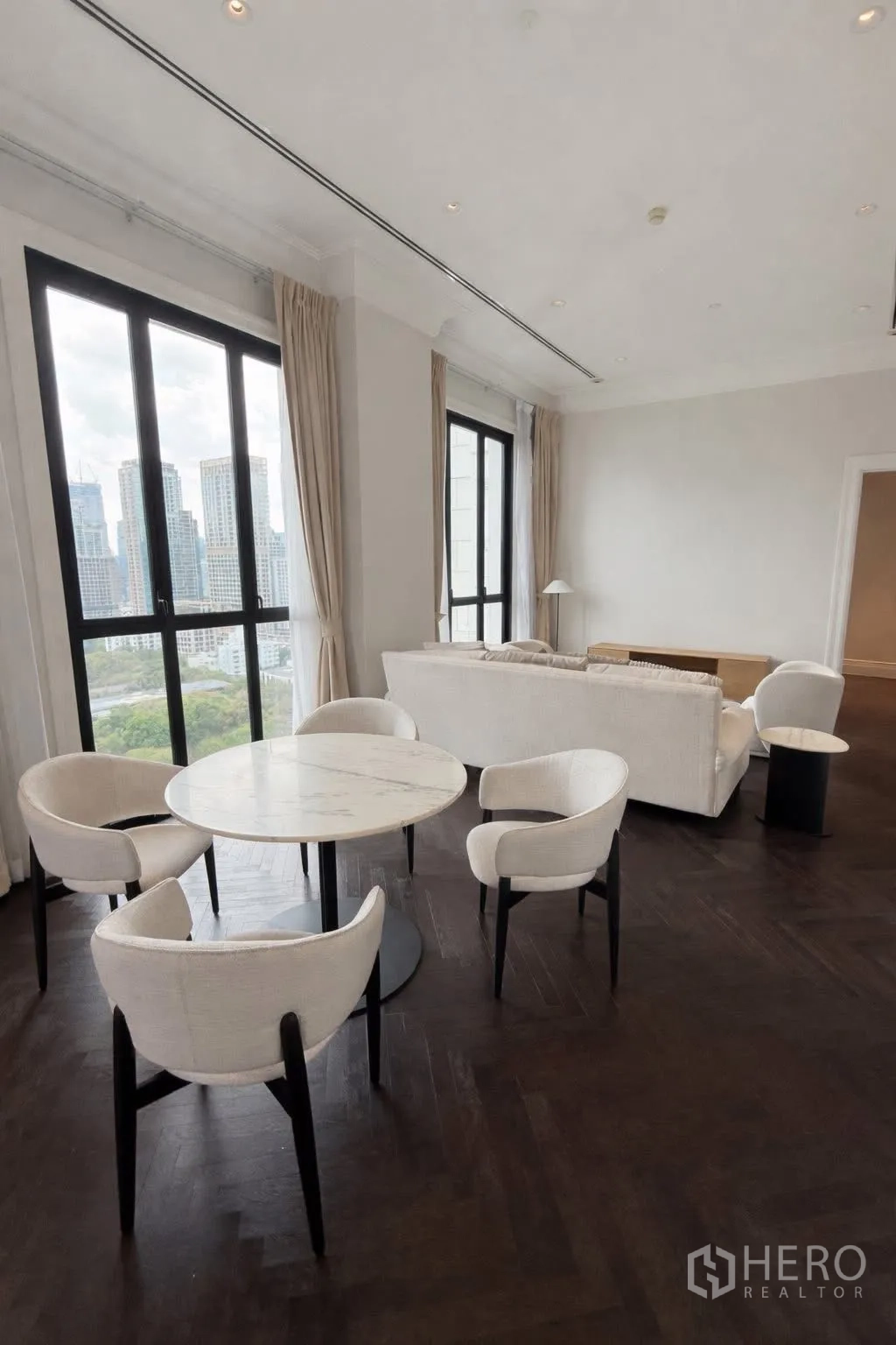 公寓 for rent or sale in Pathum Wan, Bangkok - 客餐厅一体，圆形大理石餐桌与沙发组，落地高窗呈现天际线。