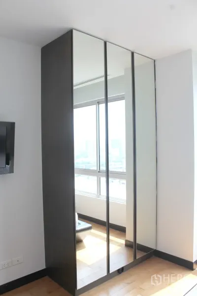 Condominium for rent or sale in Yan Nawa, Bangkok - Full-height mirrored wardrobe reflecting natural light beside the bedroom window.