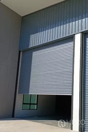 Factory for sale in Bang Bo, Samut Prakan - Close-up of tall rolling shutter door and steel-clad facade at the factory loading bay.