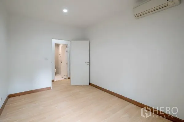 คอนโด ขาย - ห้องนอนว่างพื้นไม้ มีเครื่องปรับอากาศและทางเข้าห้องน้ำในตัว