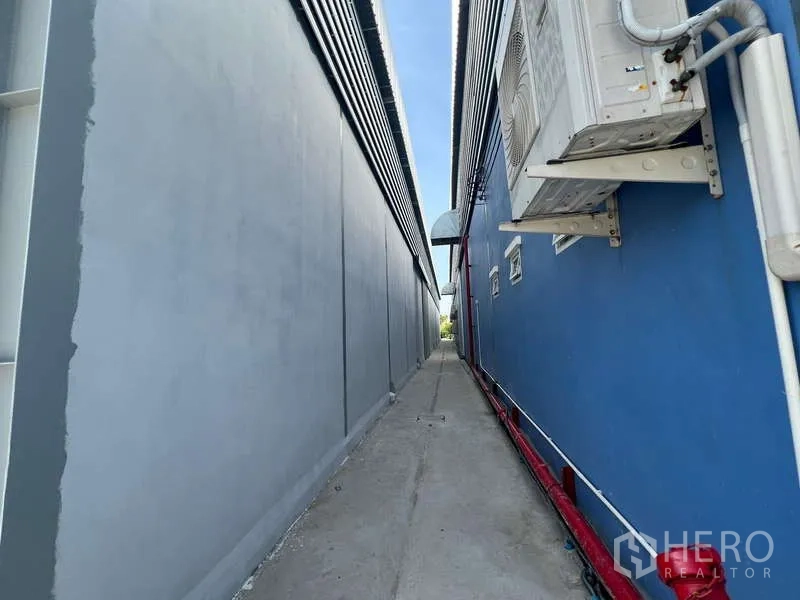 货栈 出租在Prawet, Bangkok - 仓库侧边狭长的服务通道，外置管线与空调机。