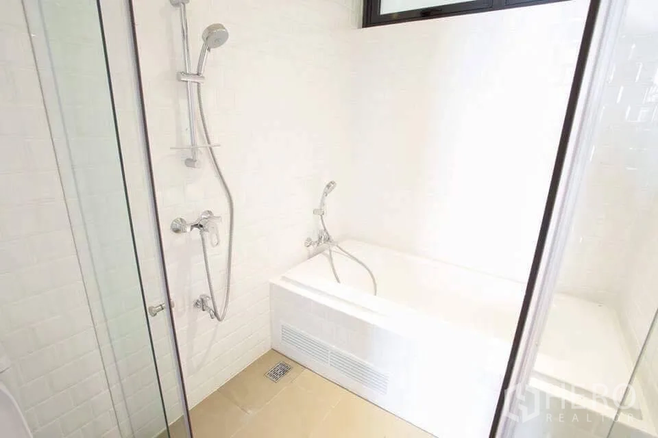 公寓 出租在Watthana, Bangkok - 浴室配独立浴缸与玻璃淋浴间，白色瓷砖墙面清爽洁净。