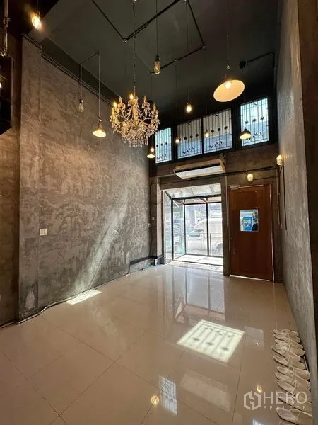 อาคารพาณิชย์ ให้เช่าในChatuchak, Bangkok - โถงหน้าร้านเพดานสูงพร้อมโคมระย้าและประตูกระจก ผนังคอนกรีต.