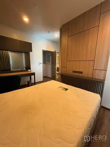 คอนโด ให้เช่าหรือขายในWatthana, Bangkok - ห้องนอนพร้อมผนังตกแต่งไม้ โต๊ะทำงานยาว และแสงไฟโทนอุ่นใกล้ประตู