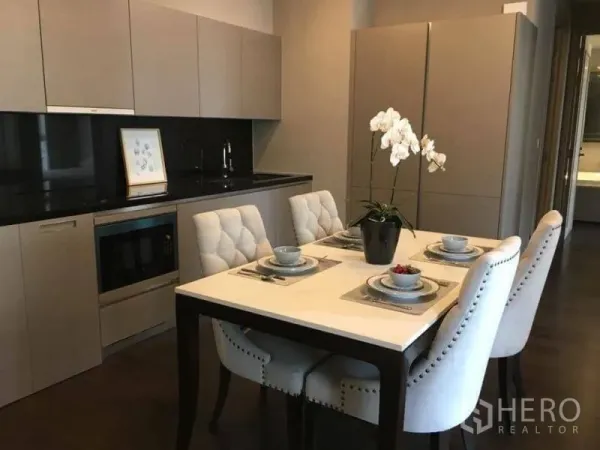 คอนโด ให้เช่าในWatthana, Bangkok - ครัวสมัยใหม่พร้อมเคาน์เตอร์หินสีดำ ตู้บิวท์อิน ไมโครเวฟ และโต๊ะทานอาหาร 4 ที่นั่งพร้อมเก้าอี้บุและแจกันกล้วยไม้