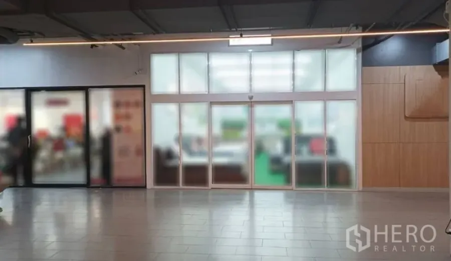零售空间 出租在Watthana, Bangkok - 室内商场店面，带大面积磨砂玻璃推拉门与瓷砖走道。
