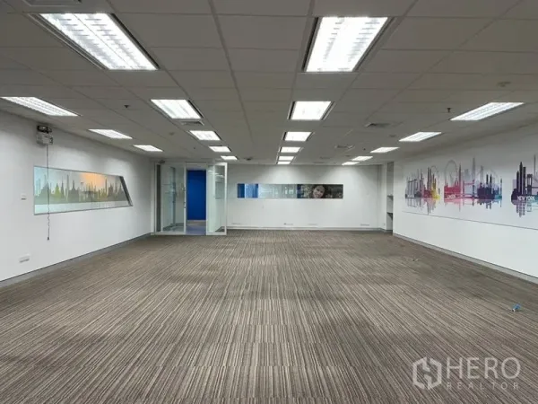 Office Space for rent - Expansive office floor with suspended light panels, a glass entry door and skyline wall graphics.