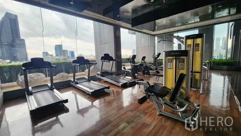 公寓 出租在Khlong Toei, Bangkok - 健身房配跑步机与力量器械，面向城市景观。