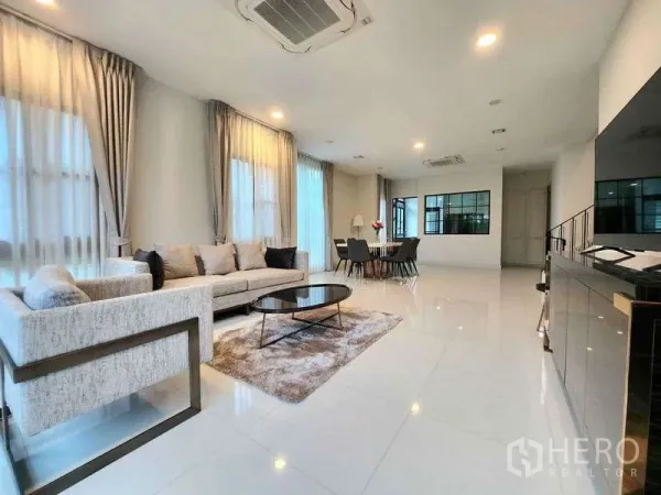Detached House for rent in Saphan Sung, Bangkok - Spacious lounge view showing dining set, recessed lighting and large windows for natural light.