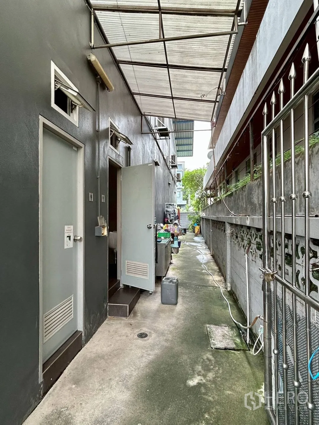 Warehouse for rent in Suan Luang, Bangkok - Rear walkway with covered roof leading to two tiled restrooms.