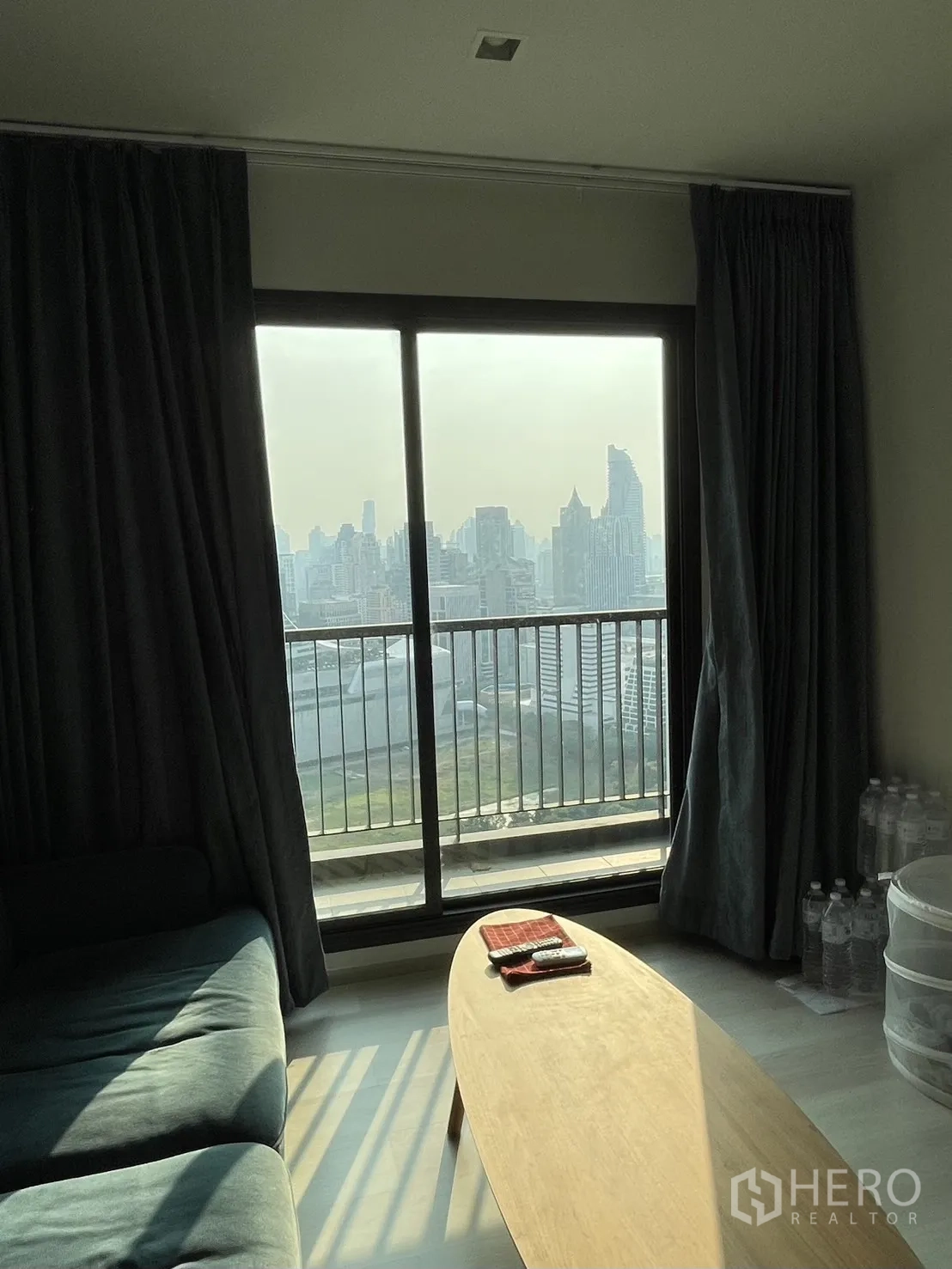 Condominium for rent in Pathum Wan, Bangkok - Living room with sliding glass doors to the balcony, coffee table and skyline beyond.