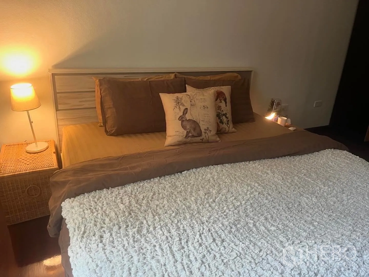Shophouse for rent in Bang Rak, Bangkok - Bedroom close-up with warm lighting and wicker bedside table.